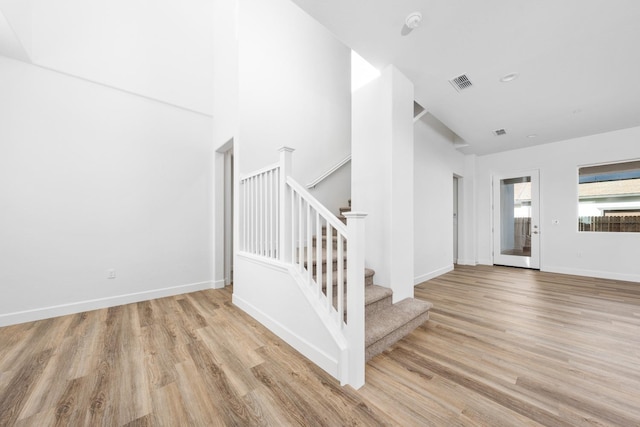 staircase with visible vents, baseboards, and wood finished floors