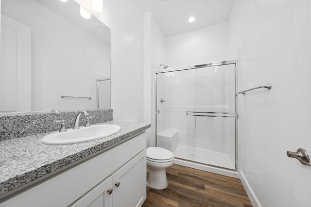 full bath featuring a stall shower, baseboards, toilet, wood finished floors, and vanity