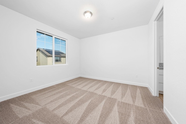 unfurnished room featuring carpet and baseboards