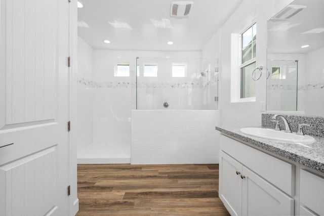 full bathroom with a walk in shower, visible vents, vanity, and wood finished floors