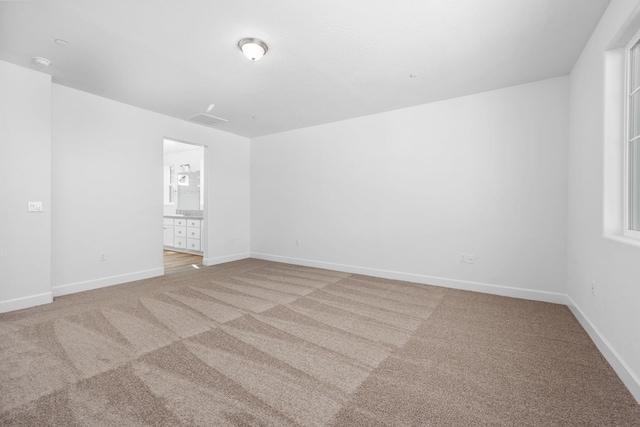 unfurnished room with baseboards, visible vents, and light colored carpet