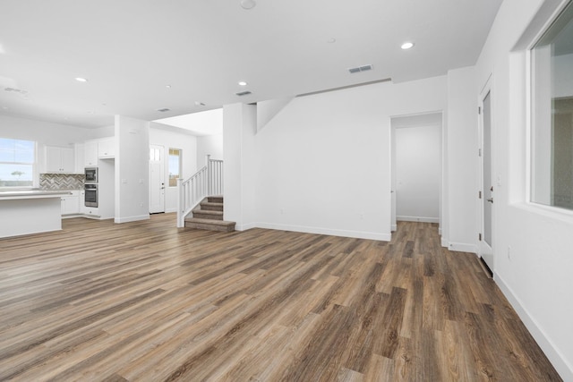 unfurnished living room featuring recessed lighting, visible vents, stairway, light wood-style floors, and baseboards