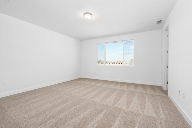 unfurnished room with light colored carpet, visible vents, and baseboards