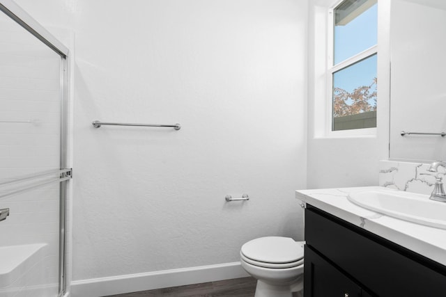 full bath featuring baseboards, an enclosed shower, vanity, wood finished floors, and toilet