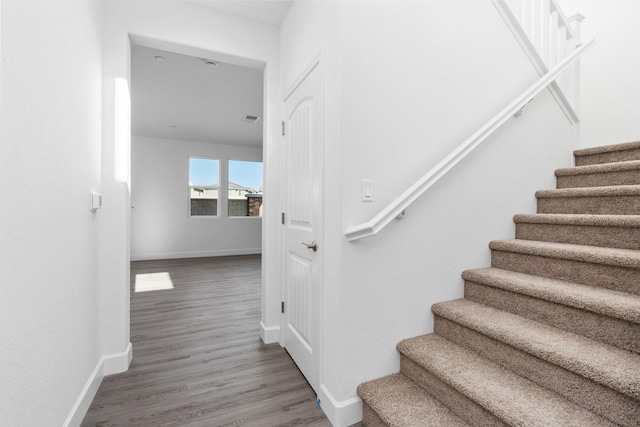 stairs with visible vents, baseboards, and wood finished floors