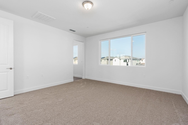 carpeted spare room featuring visible vents and baseboards