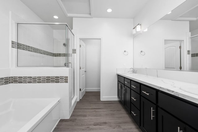 bathroom with wood finished floors, double vanity, a stall shower, a sink, and a bath