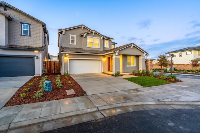 view of front of property with concrete driveway, stucco siding, a garage, fence, and a tiled roof