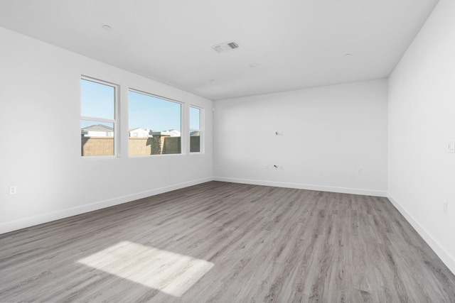 unfurnished room with wood finished floors, visible vents, and baseboards