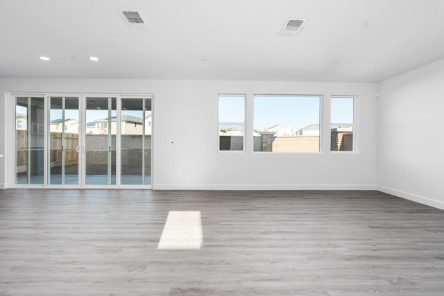 spare room with visible vents, plenty of natural light, and wood finished floors