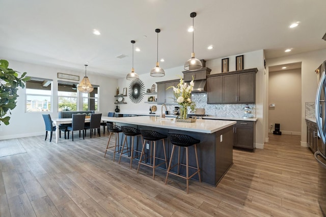 1007 Highland Rd W, Madera, CA 93636 - kitchen with light countertops, a kitchen island with sink, a breakfast bar, decorative backsplash, and recessed lighting