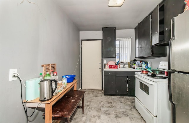 kitchen featuring white range oven, sink, and stainless steel fridge