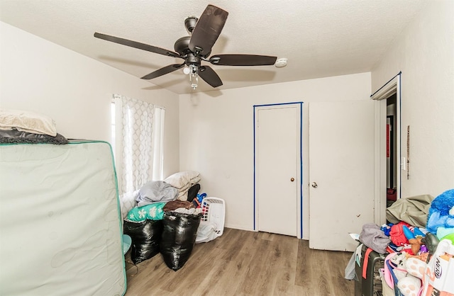 bedroom featuring ceiling fan, a textured ceiling, and light hardwood / wood-style floors