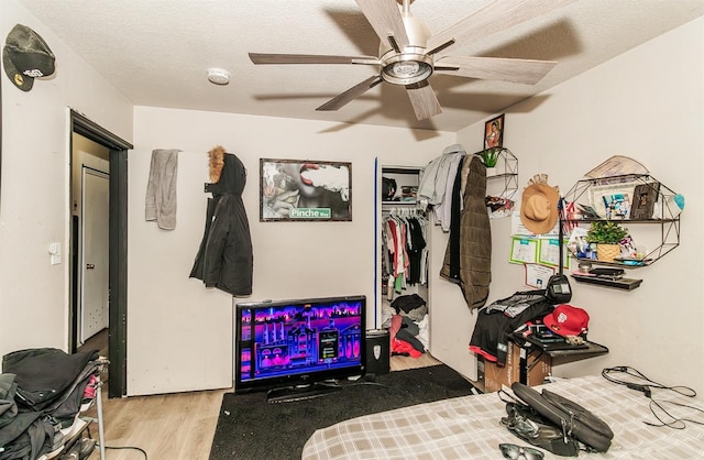 workout room with ceiling fan, a textured ceiling, and light hardwood / wood-style floors