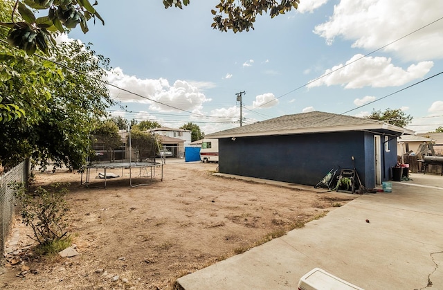 view of home's exterior with a trampoline, a patio area, and an outbuilding