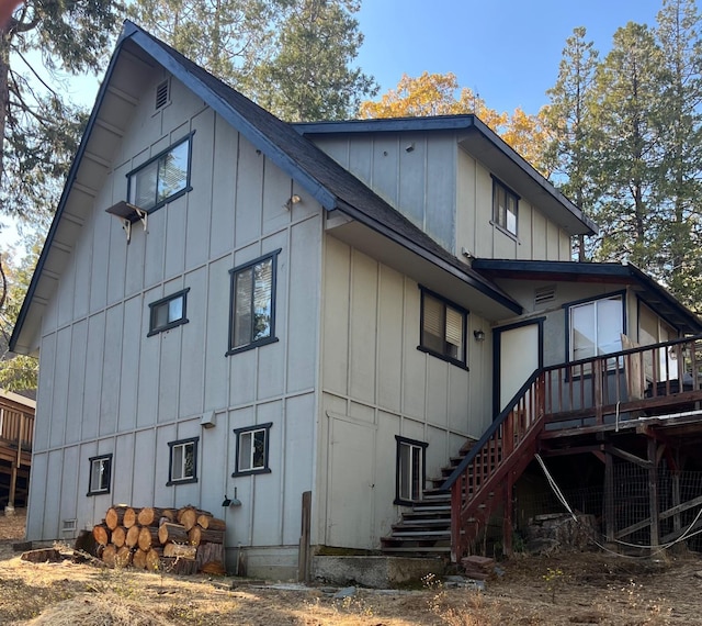 back of house with stairway, board and batten siding, and a wooden deck