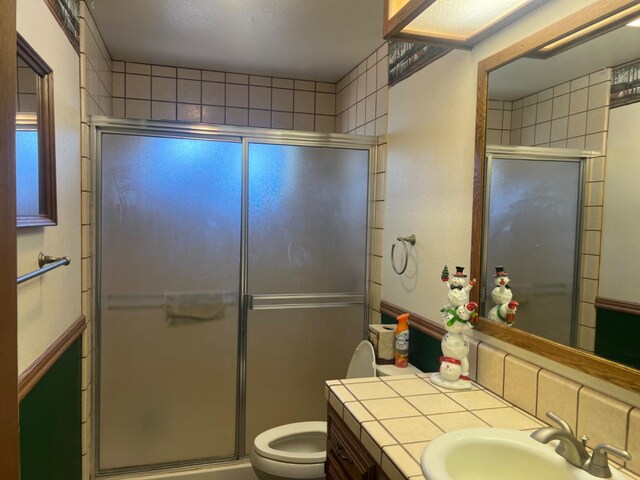 bathroom with a shower with door, vanity, and toilet