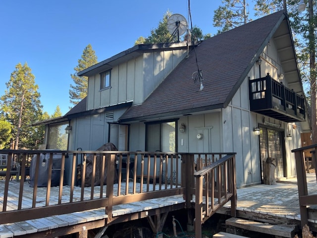 rear view of house featuring a shingled roof, a chimney, and board and batten siding