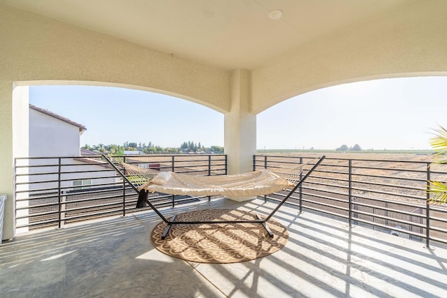 view of patio with a balcony and a rural view