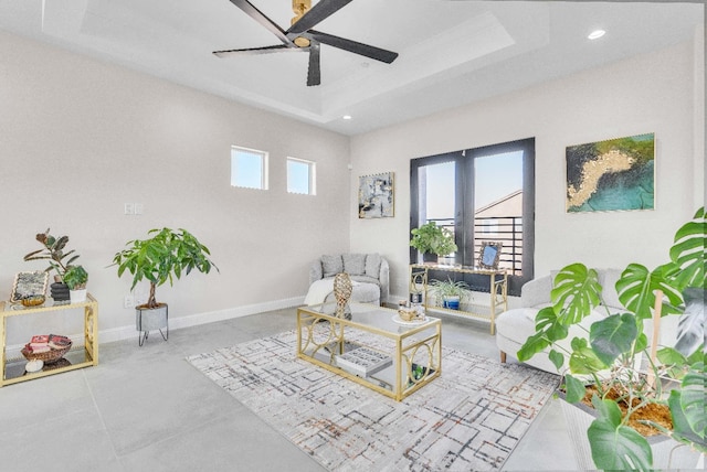 living room with a tray ceiling and ceiling fan