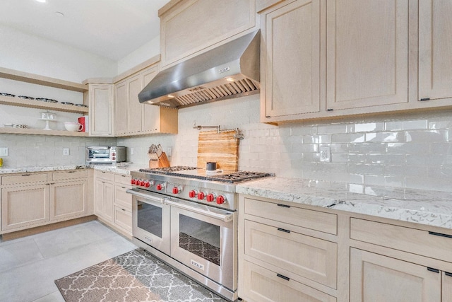 kitchen featuring wall chimney exhaust hood, light tile patterned floors, tasteful backsplash, and double oven range