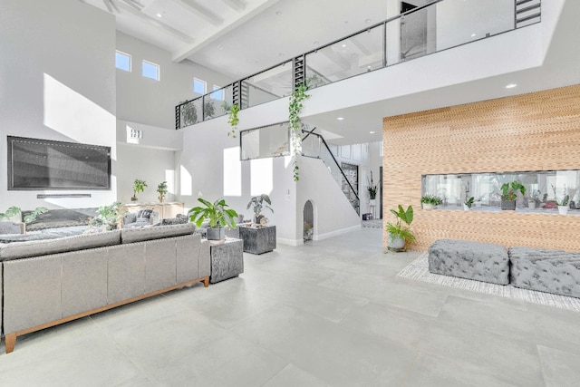 living room featuring beamed ceiling, a towering ceiling, and a healthy amount of sunlight