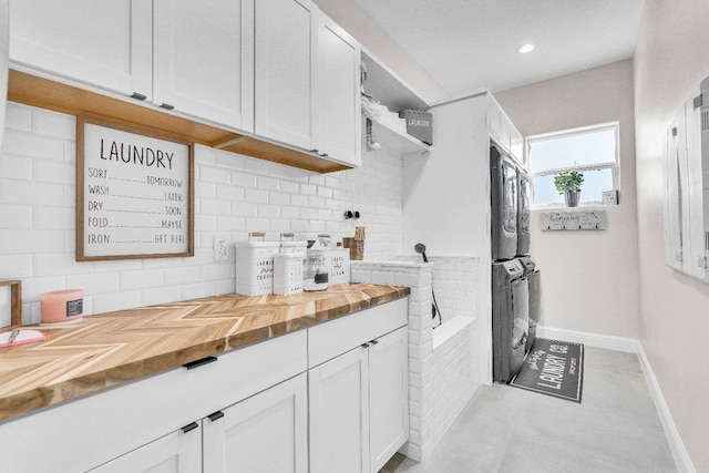 kitchen with white cabinetry, butcher block countertops, and stacked washer / drying machine