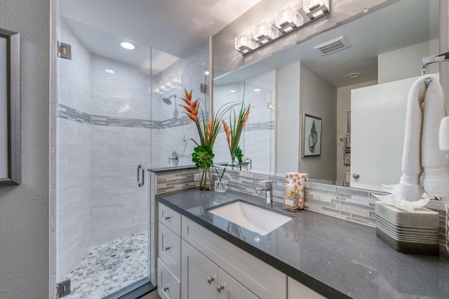 bathroom with tasteful backsplash, vanity, and a shower with door