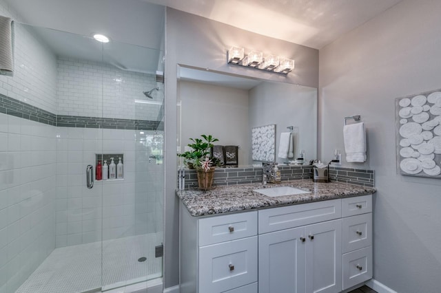 bathroom with vanity, a shower with shower door, and tasteful backsplash