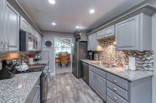 kitchen with sink, gray cabinetry, light hardwood / wood-style flooring, stainless steel appliances, and decorative backsplash