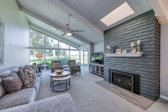 living room featuring floor to ceiling windows, lofted ceiling with skylight, light colored carpet, ceiling fan, and a fireplace