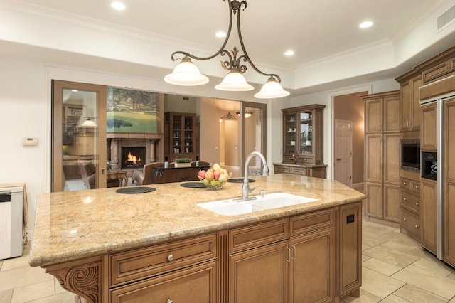 kitchen with a spacious island, hanging light fixtures, sink, and light stone counters