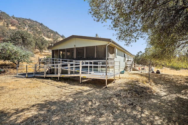 back of property with a sunroom and a mountain view