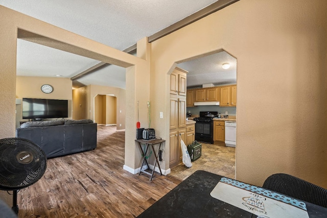 kitchen featuring light hardwood / wood-style floors, lofted ceiling with beams, dishwasher, a textured ceiling, and black range with electric cooktop