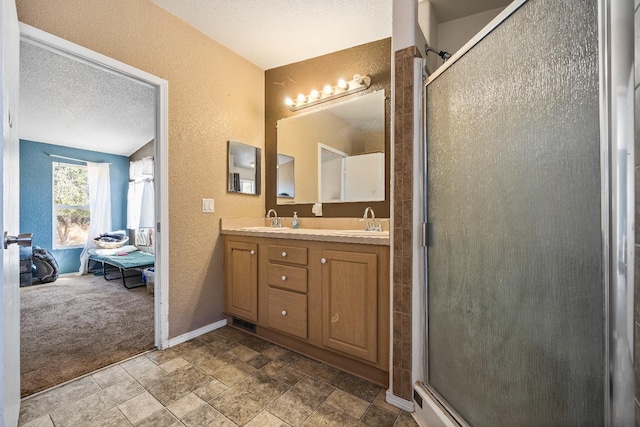 bathroom with a textured ceiling, vanity, and an enclosed shower