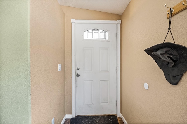 doorway to outside with baseboards and vaulted ceiling