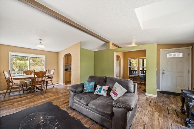 living room featuring vaulted ceiling with beams, a textured ceiling, and dark hardwood / wood-style floors