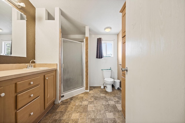 bathroom with walk in shower, vanity, toilet, and a healthy amount of sunlight