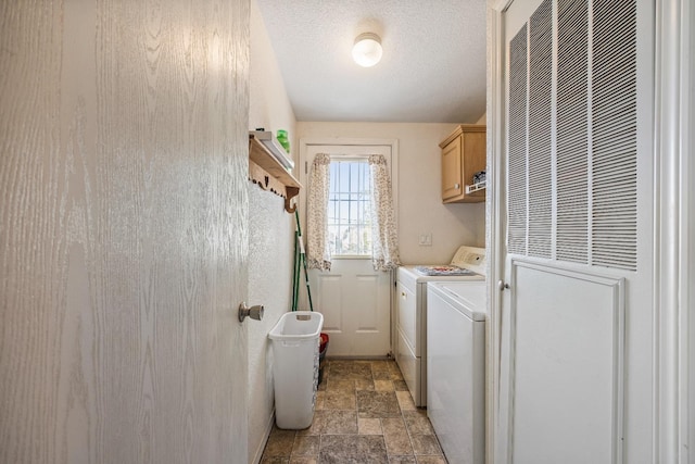 laundry room featuring cabinets, a textured ceiling, and washer and clothes dryer