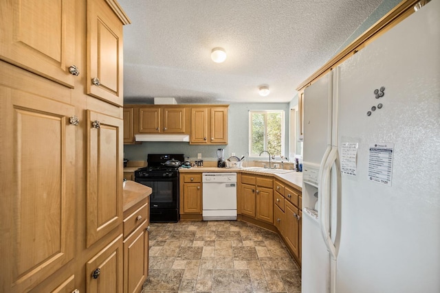 kitchen featuring light countertops, white appliances, stone finish floor, under cabinet range hood, and a sink