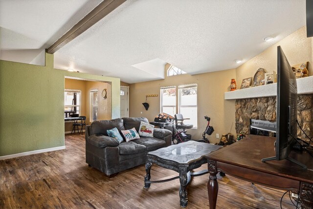 living room featuring a textured ceiling, dark wood-type flooring, and a stone fireplace