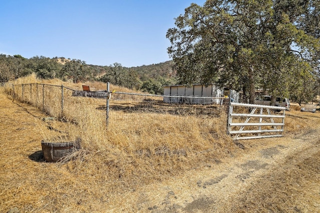 view of yard with an outbuilding, fence, and a rural view
