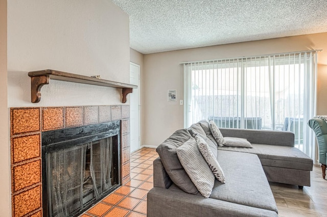 living room with a tile fireplace, a textured ceiling, and baseboards