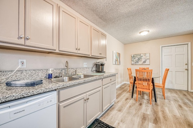 kitchen with baseboards, dishwasher, light wood-style flooring, a textured ceiling, and a sink