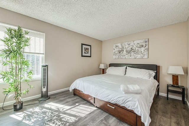 bedroom with a textured ceiling, baseboards, and wood finished floors