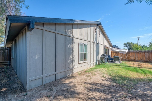 view of property exterior featuring board and batten siding, a fenced backyard, and a lawn