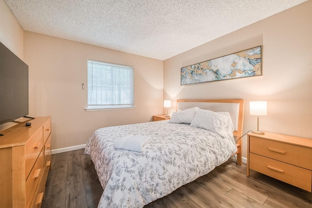 bedroom with dark wood-style flooring, a textured ceiling, and baseboards