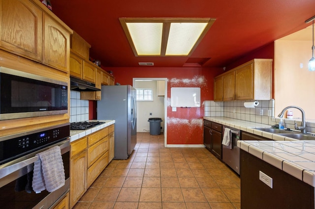 kitchen featuring tile counters, sink, decorative backsplash, appliances with stainless steel finishes, and light tile patterned floors