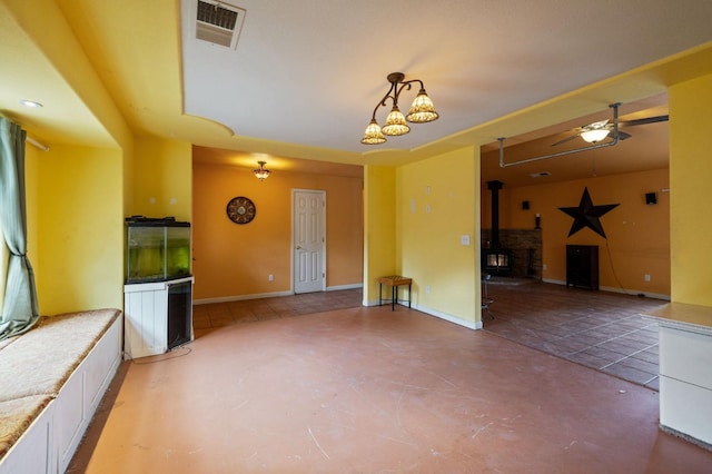 empty room with concrete floors, ceiling fan, and a wood stove