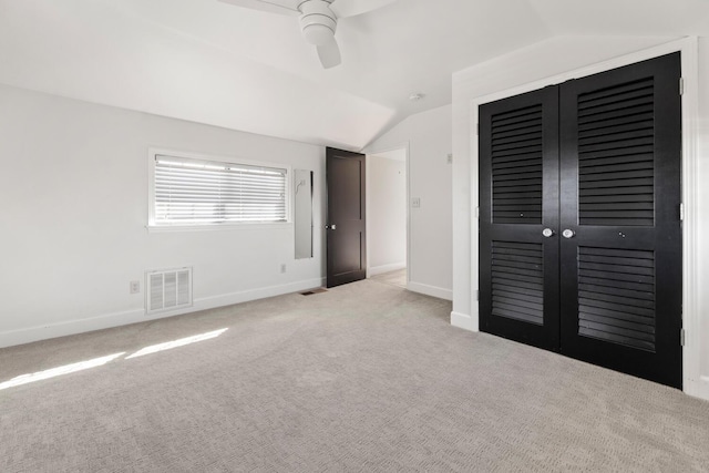 unfurnished bedroom with ceiling fan, lofted ceiling, light colored carpet, and a closet